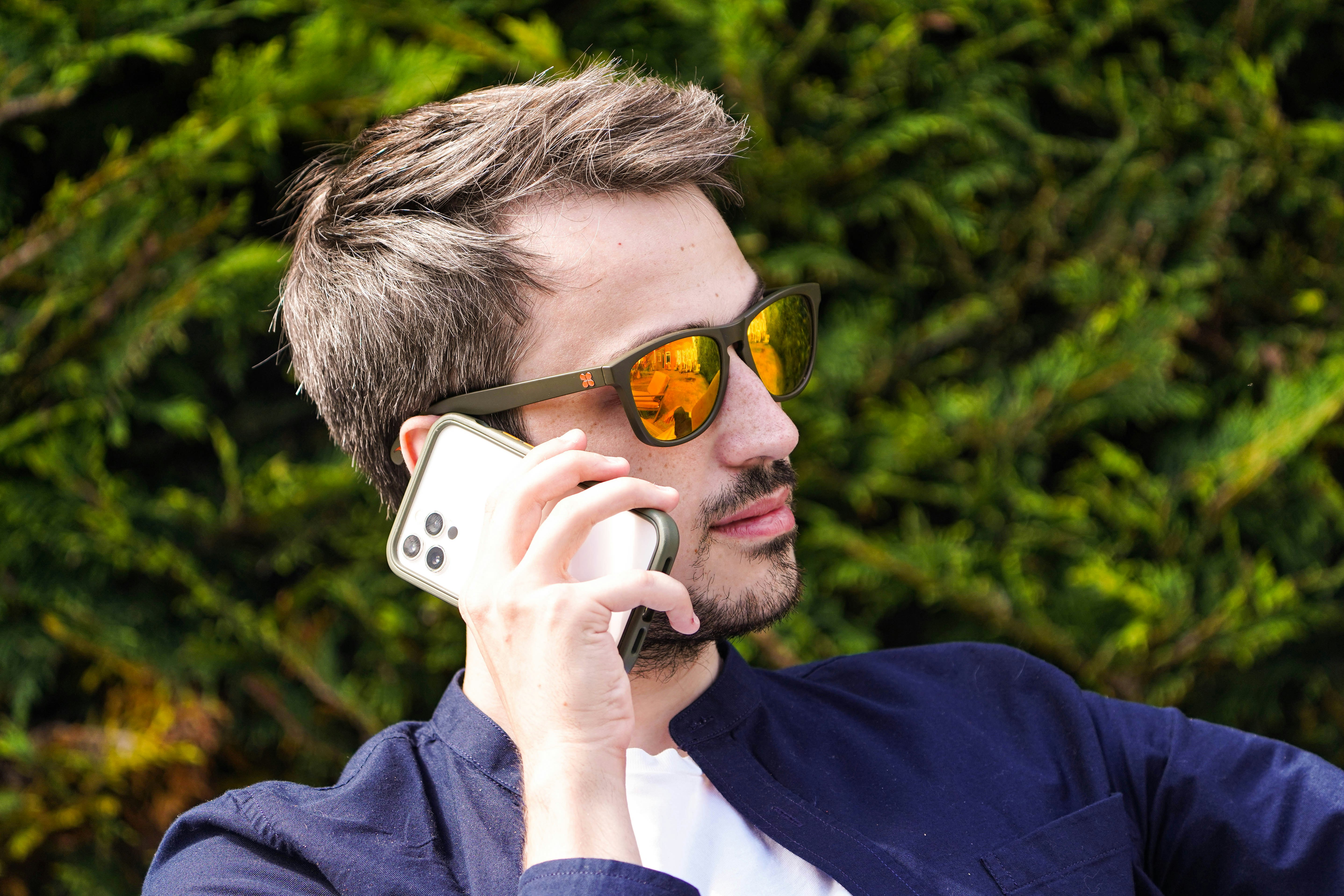 a man wearing sunglasses and holding a cell phone to his ear