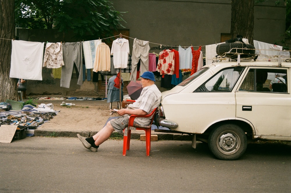 a man sitting in a chair next to a car