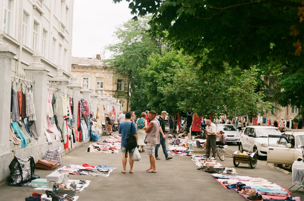 a group of people walking in a street with tents and cars