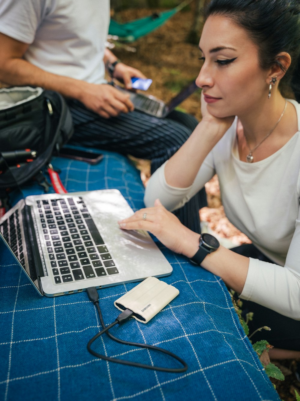 a woman sitting at a table with a laptop and a phone