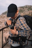 An outdoor enthusiast adjusting a thermal scanner while perched on a rocky outcrop.