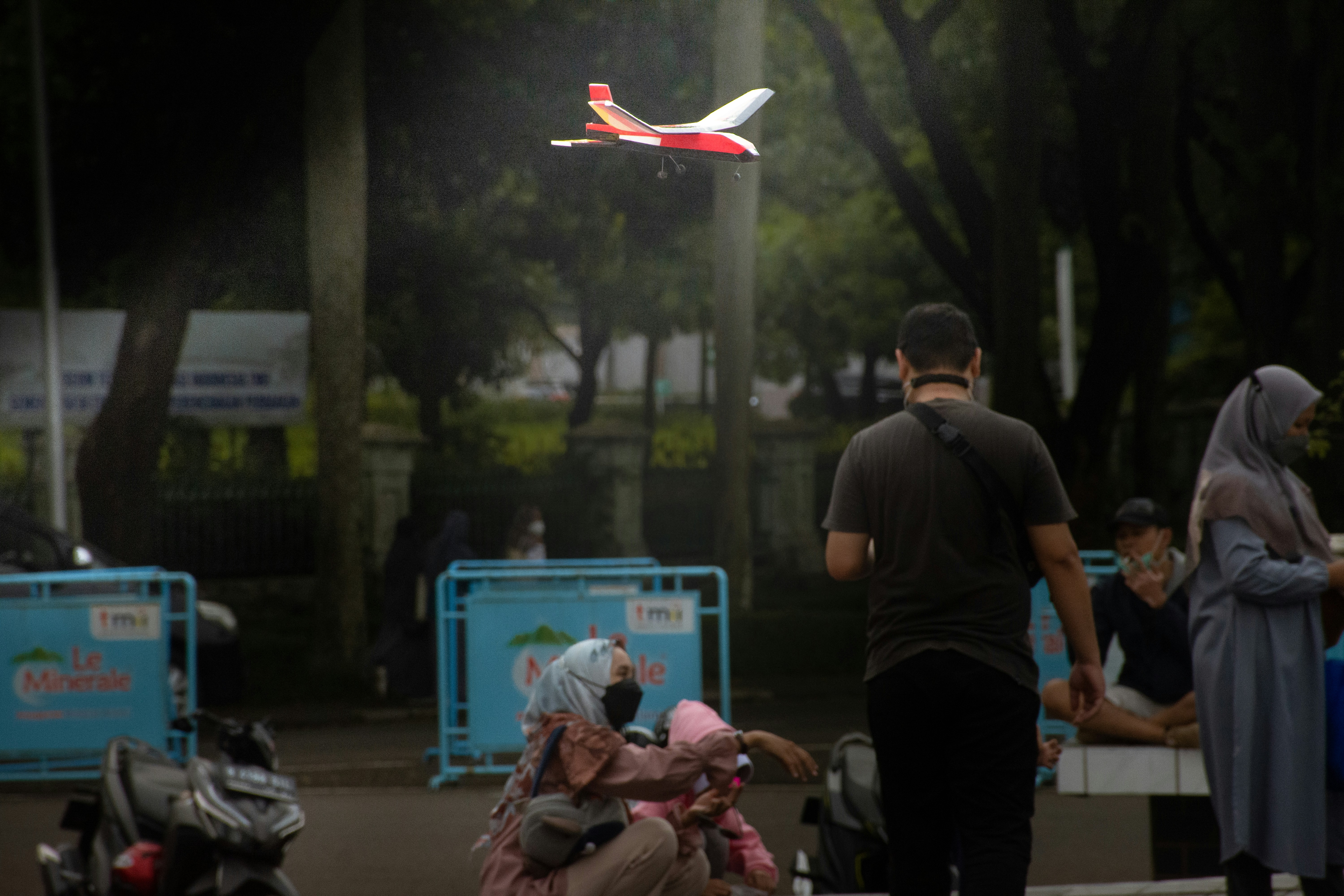 seseorang yang berdiri di samping seseorang yang tergeletak di tanah dengan drone terbang di udara