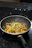 Close-up of a sleek non-stick stir fry pan on a modern stovetop with fresh vegetables nearby.