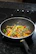 Close-up of a sleek non-stick stir fry pan on a modern stovetop with fresh vegetables nearby.