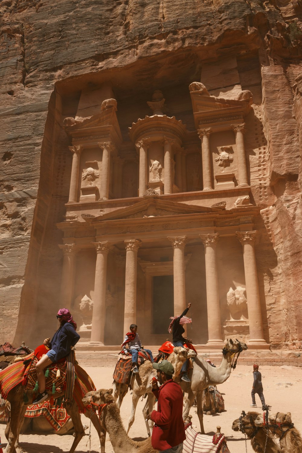 a group of people riding horses in front of Petra