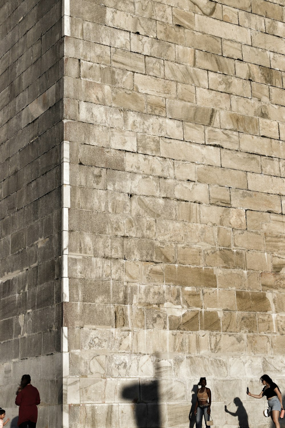 a group of people standing next to a brick wall