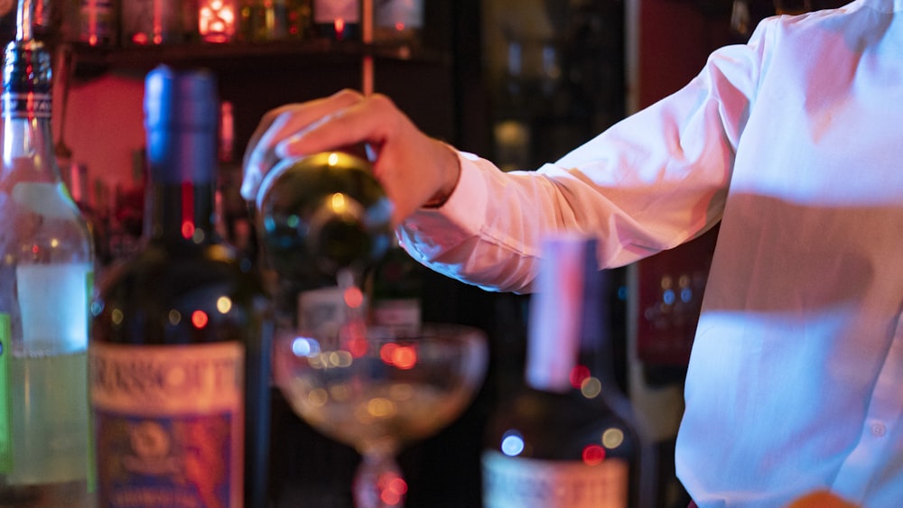 a person pouring a drink into a glass