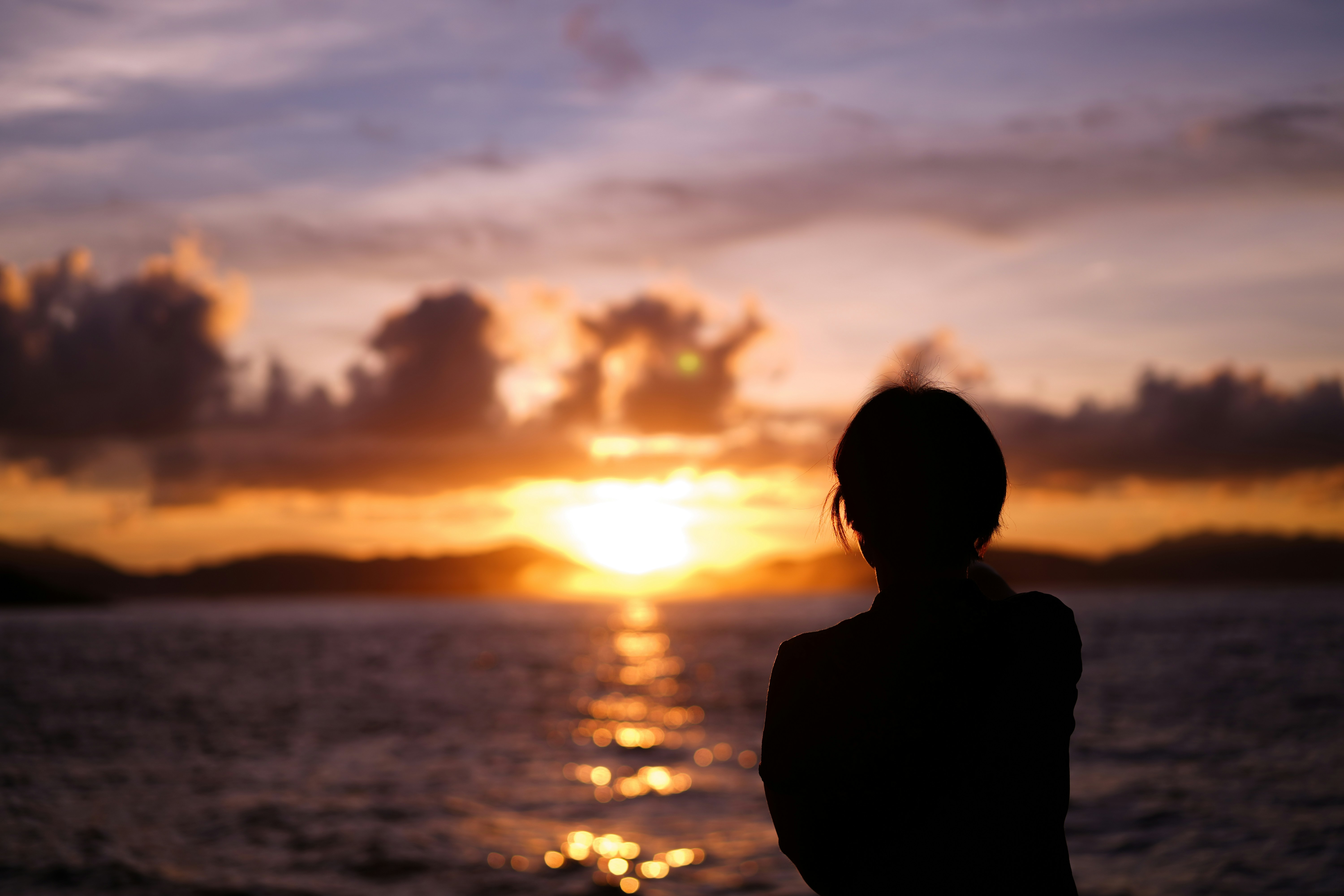 A person looking at a beautiful, expansive sunrise, symbolizing the unknown future and new beginnings.