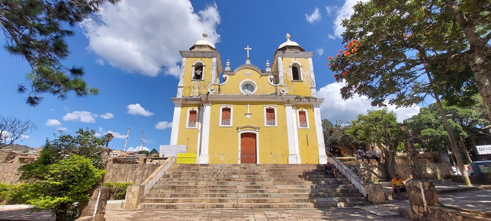 a yellow building with stairs and a cross on top