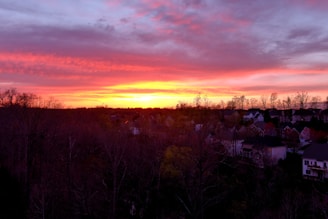 A colorful sunset casting warm hues over a suburban neighborhood.