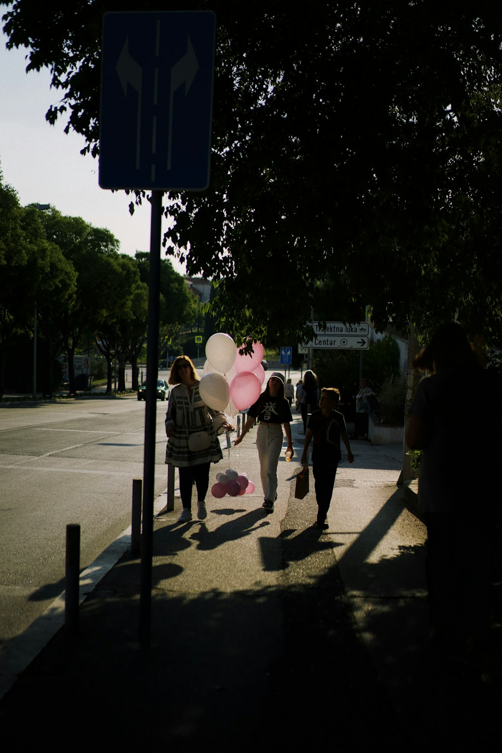 people walking down a sidewalk with pink umbrellas