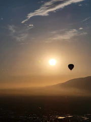 An elegant hot air balloon drifting over the Nile at sunrise, with a golden sky backdrop.
