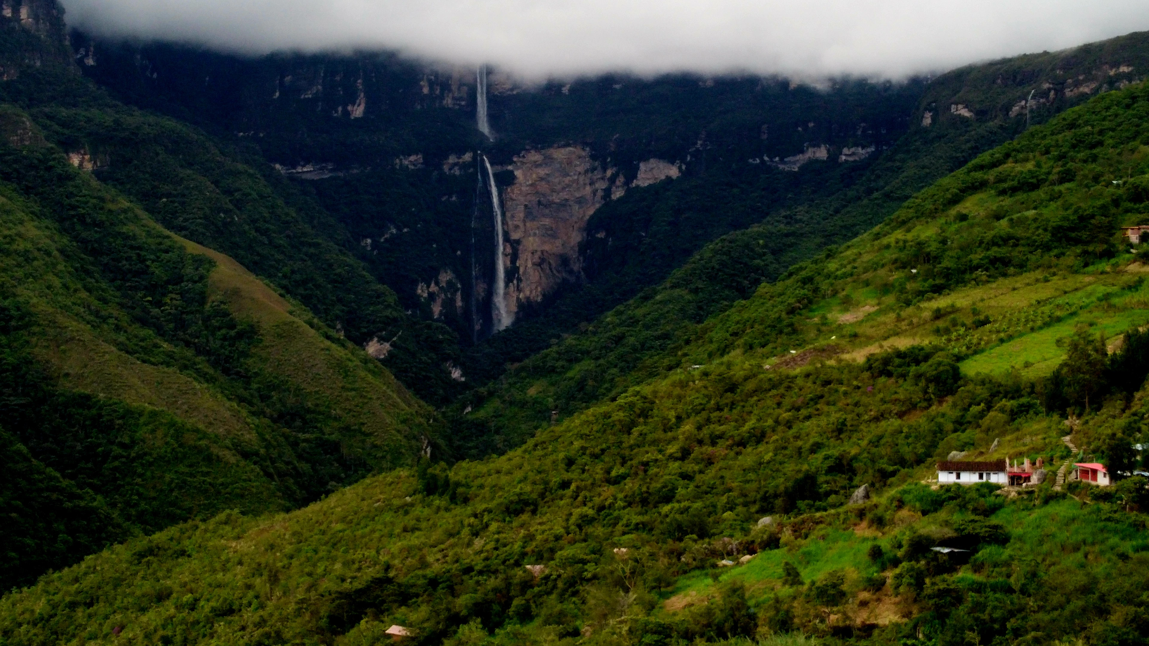 The Gocta falls dropping from a clouded cliff into a green valley near the village of Cocachimba