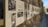 A long display of historical photographs and text is mounted along a textured stone wall. The images are likely black and white, some featuring group portraits and scenes from the past with accompanying text in a language possibly Hebrew. The setting is outdoors, with a blurred background suggesting depth and focus on the pictures.