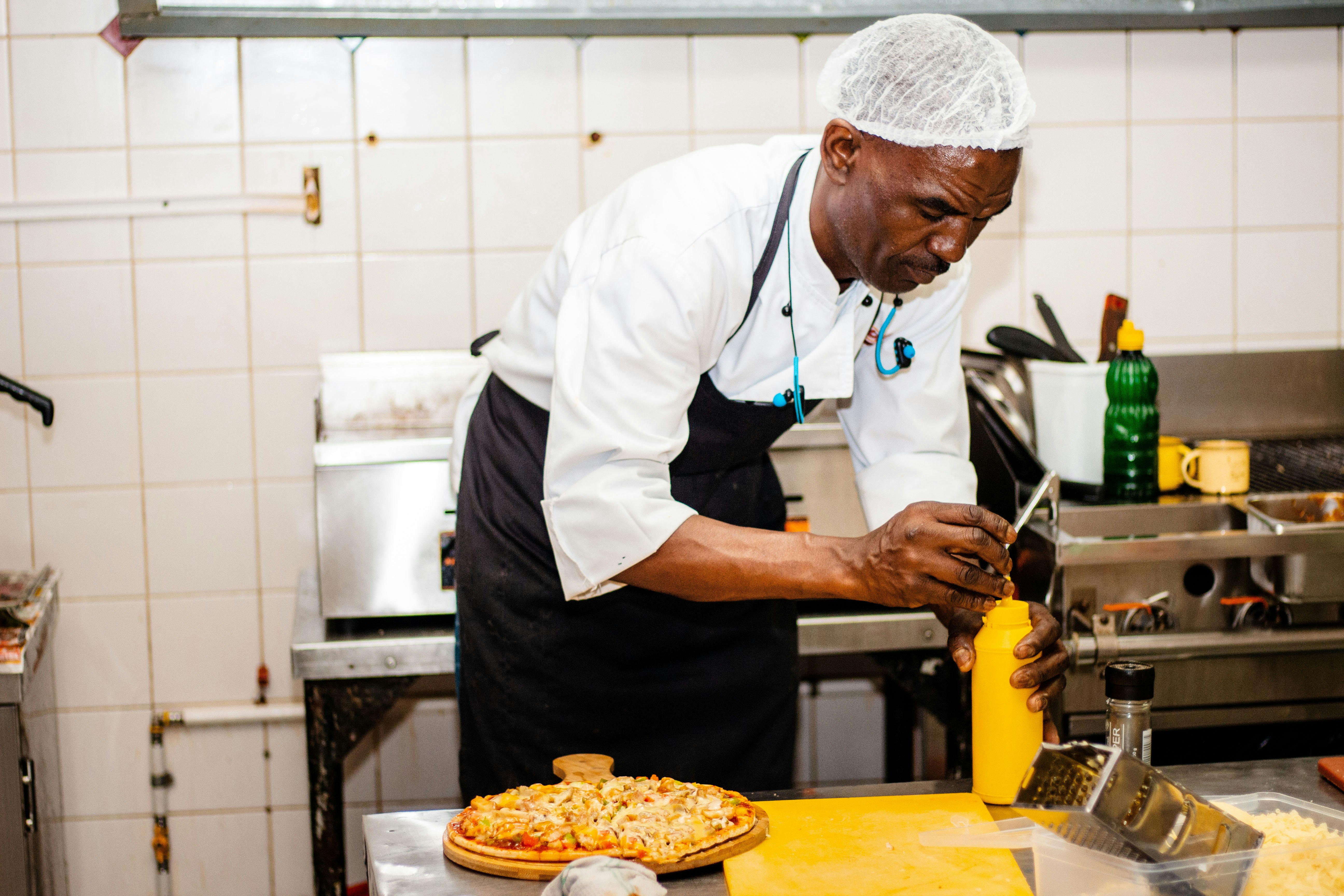 Chef in white cooking at the stove in a tiled kitchen