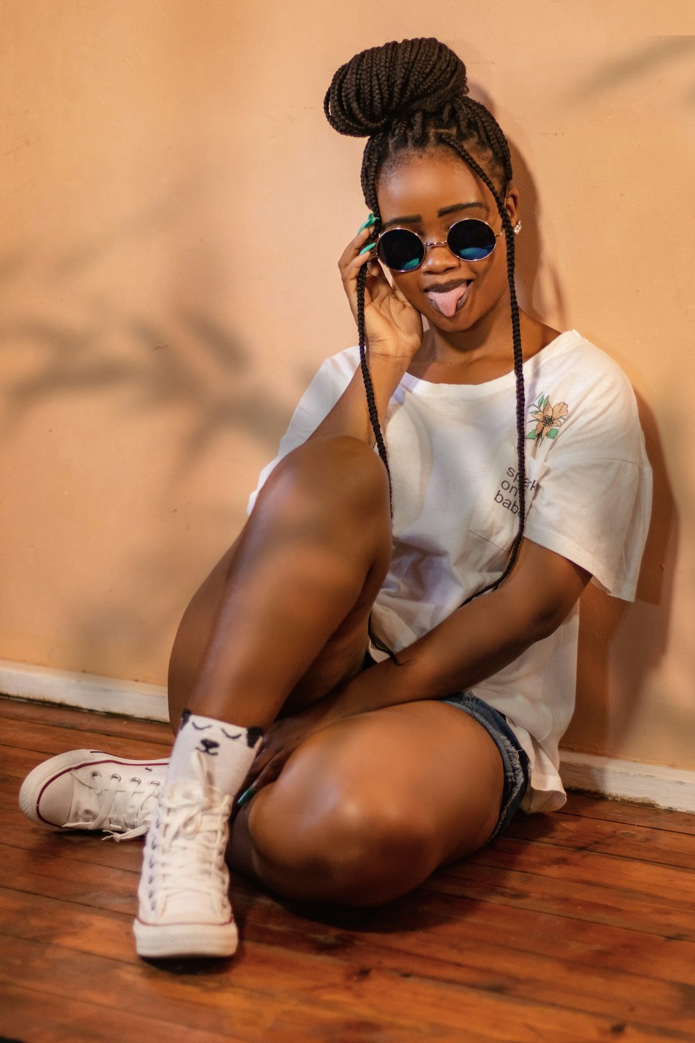 a woman wearing sunglasses and a white shirt sitting on the floor