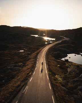 Sunrise over rolling hills with a lone gravel cyclist in the distance.