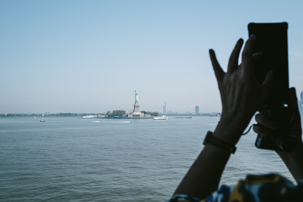 a person taking a picture of a body of water with a boat in it