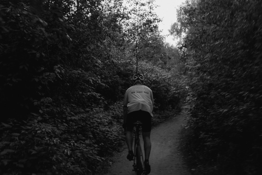 a man riding a bicycle on a path in the woods