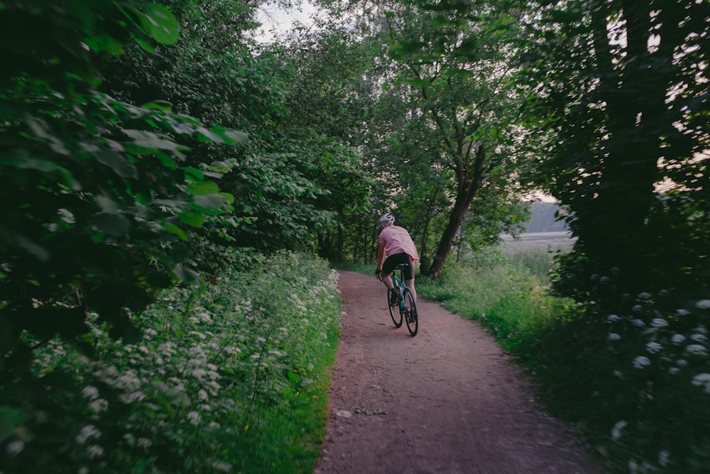 a person riding a bike on a path surrounded by trees