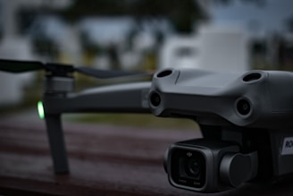 Professional DJI drone resting on a wooden surface outdoors, with blurred background of trees