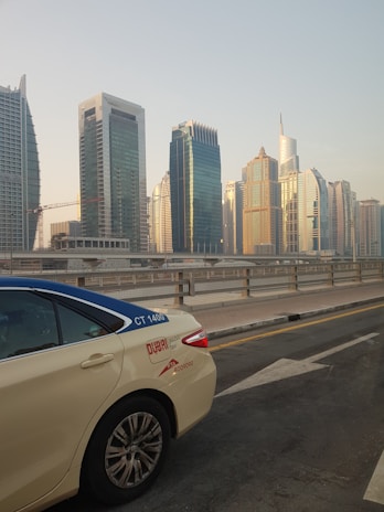 A clean and modern taxi parked in front of a city skyline.