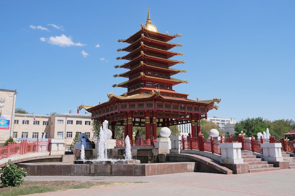 a red asian building with a fountain in front of it