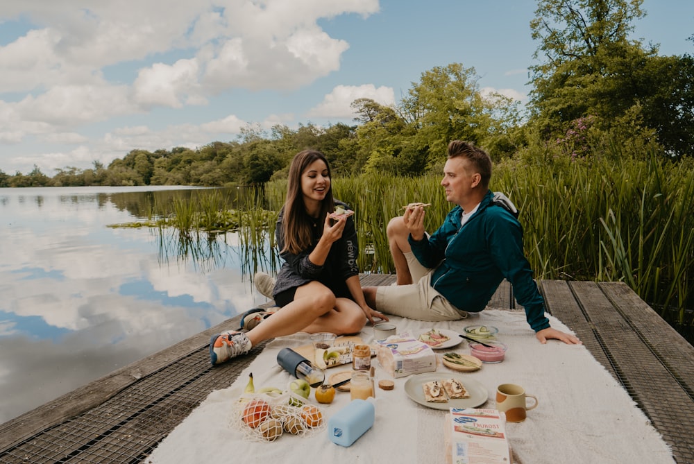 a man and woman sitting at a table with food and drinks