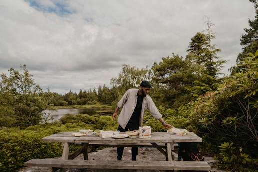 A folding table arranged outdoors with picnic food and nature in the background.