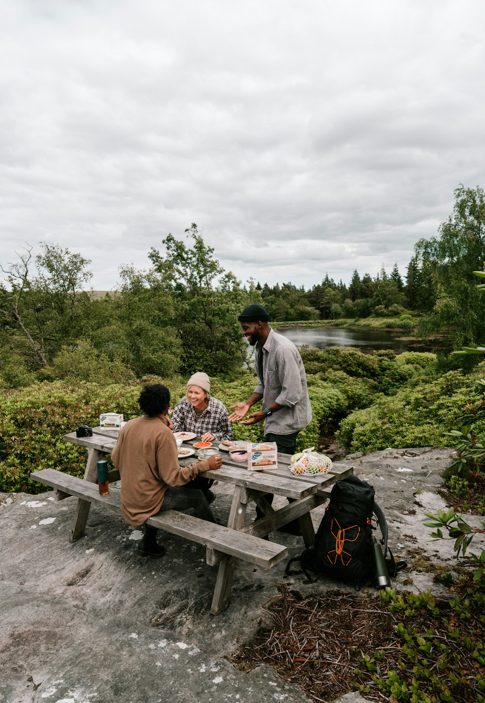 a group of people sitting at a picnic table in a forest