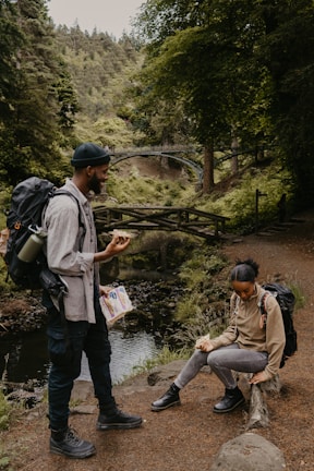 Close-up of smiling runners sharing stories during a break beside a flowing stream.