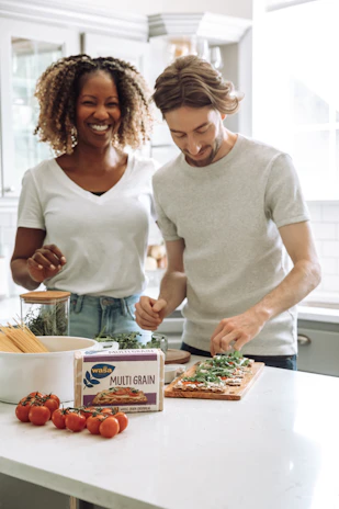 A confident middle-aged man and woman reviewing health supplements together in a bright, modern kitchen.