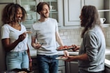 Friends laughing and sharing slices of pizza around a cozy table lit by warm ambient lighting.