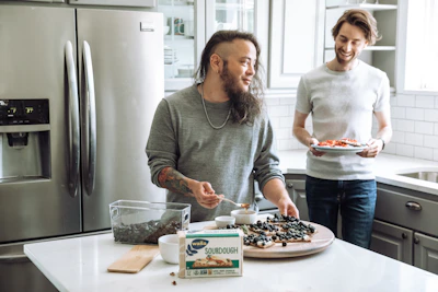 Two support workers sharing a light moment while preparing a meal together.