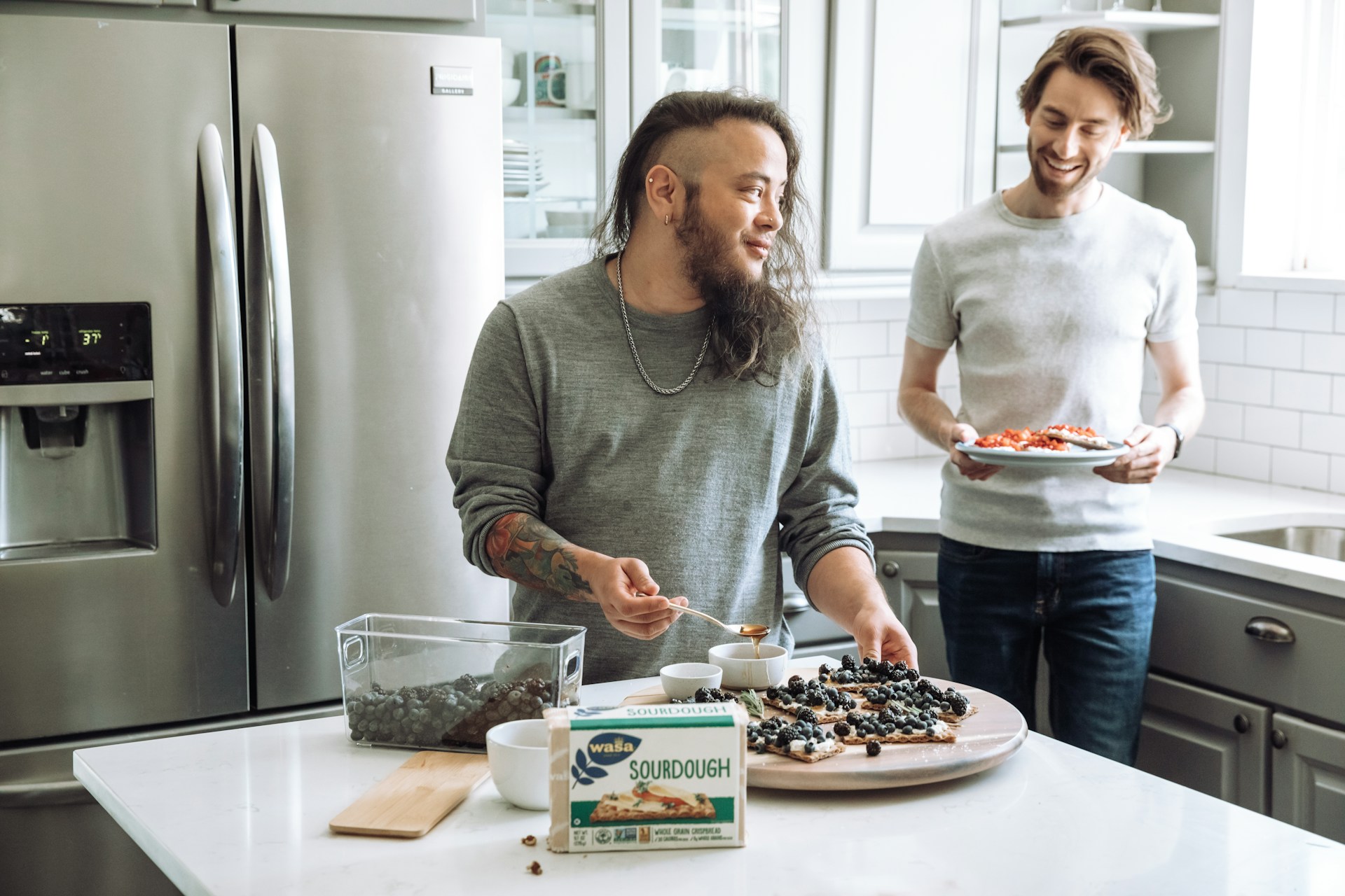 a couple of men stand near each other holding pizzas