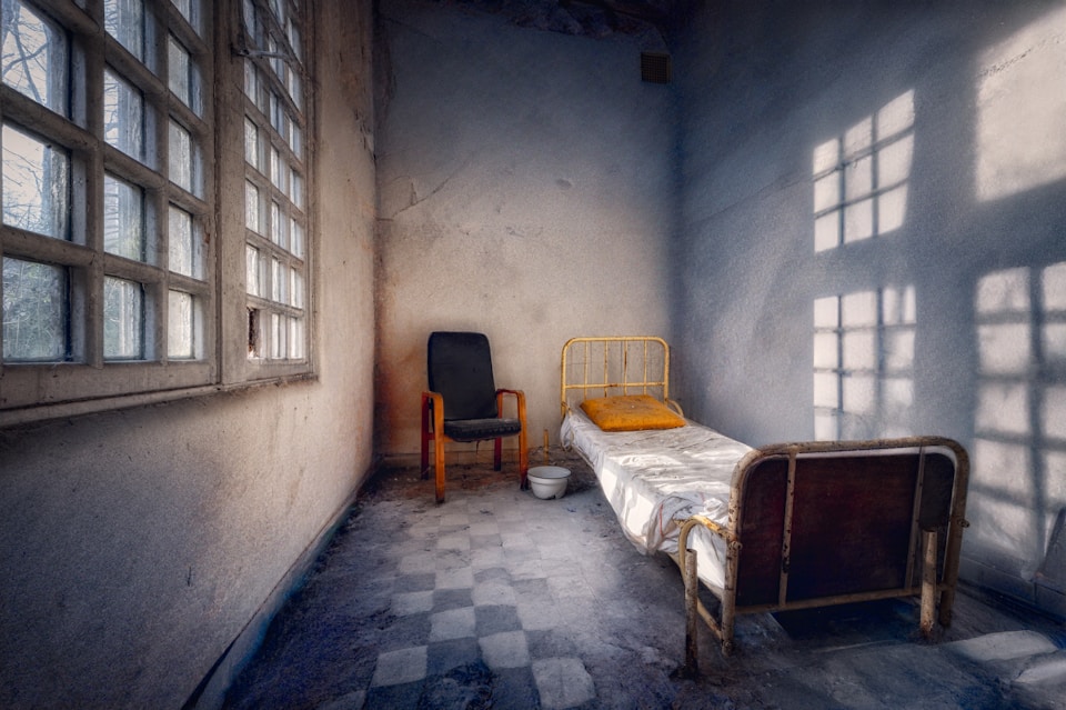 A prison cell with a bed and a chair