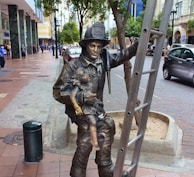 a statue of a man holding a sword on a sidewalk