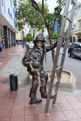 a statue of a man holding a sword on a sidewalk