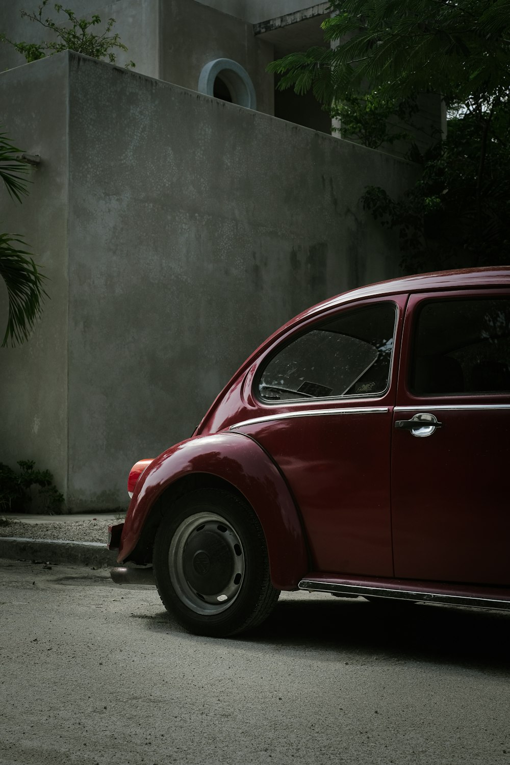 a red car parked next to a concrete wall