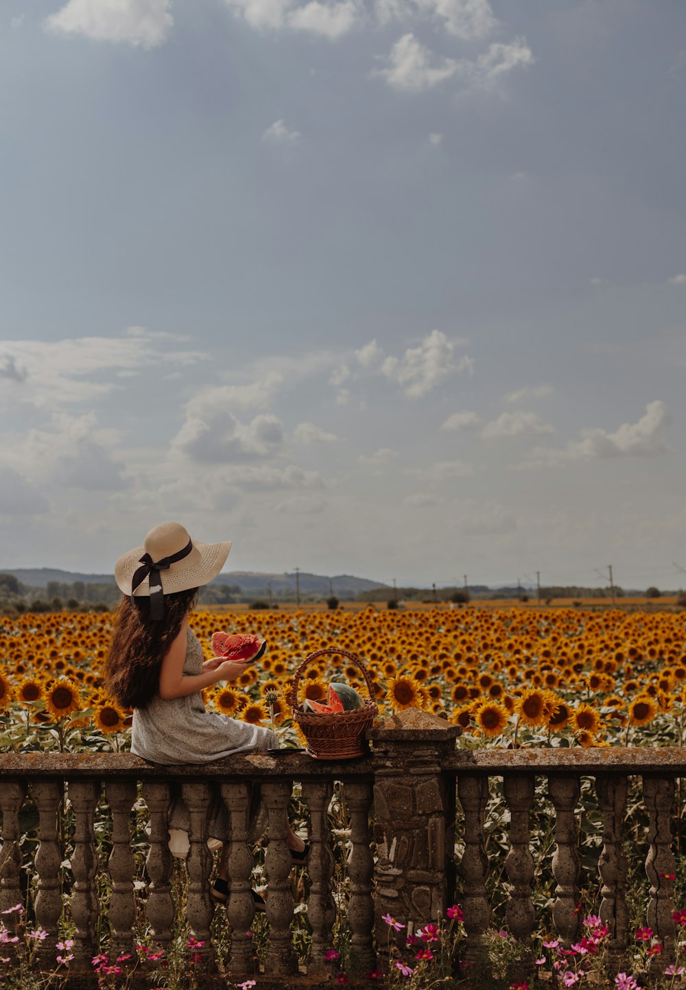 a person sitting in a field of flowers with a basket of flowers