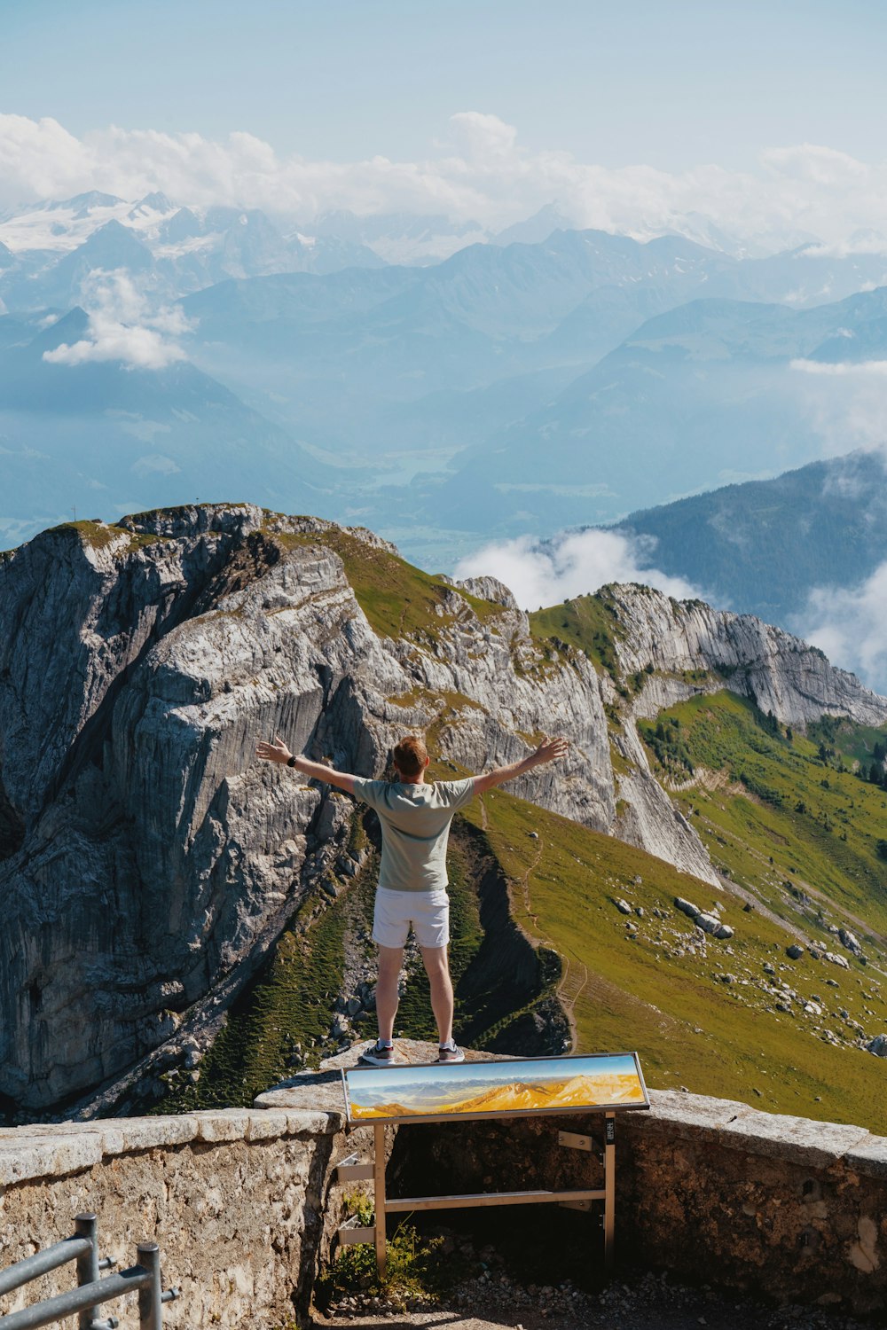 a man standing on a ledge overlooking a mountain range