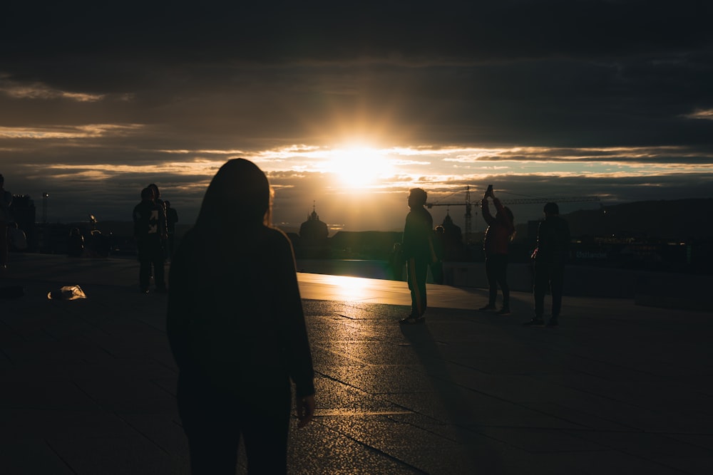 a group of people standing on a dock at sunset