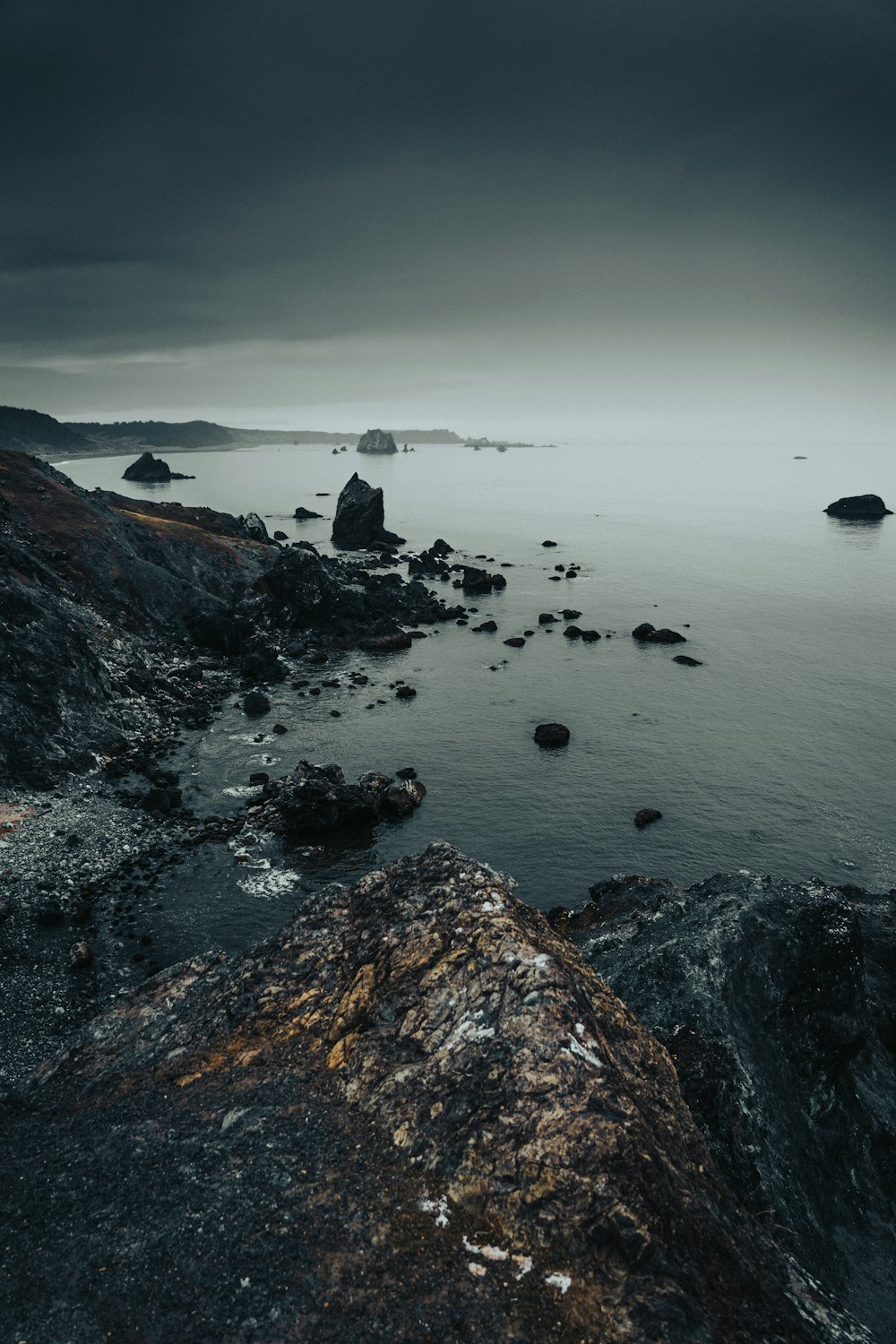 a rocky beach with a body of water in the background