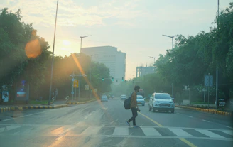 Runner crossing a city street at dawn, with soft morning light and empty roads.