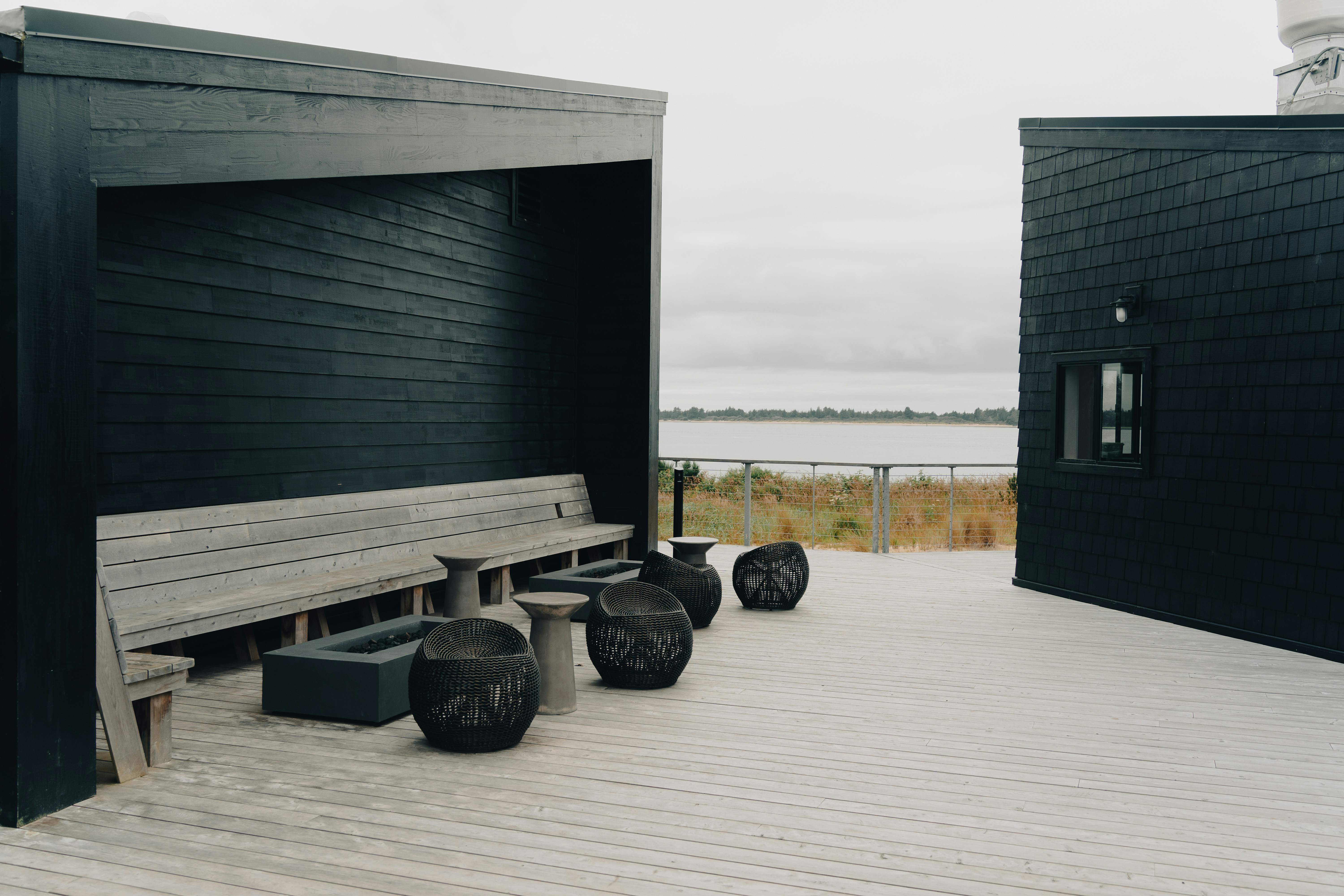 ベンチのあるウッドデッキと、背景に水域がある建物