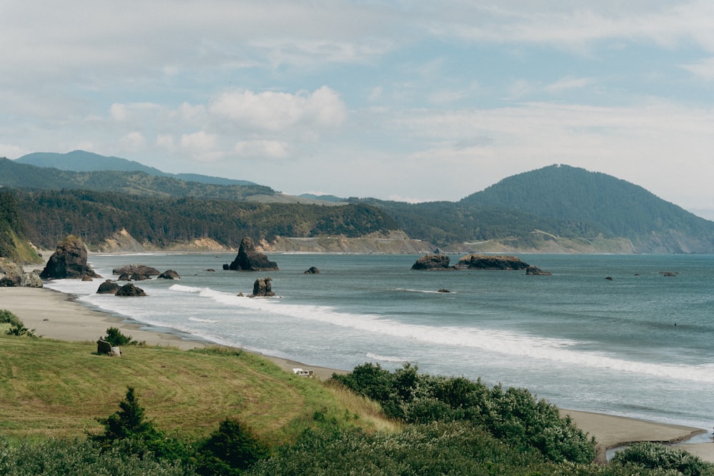 a beach with a body of water and hills in the background