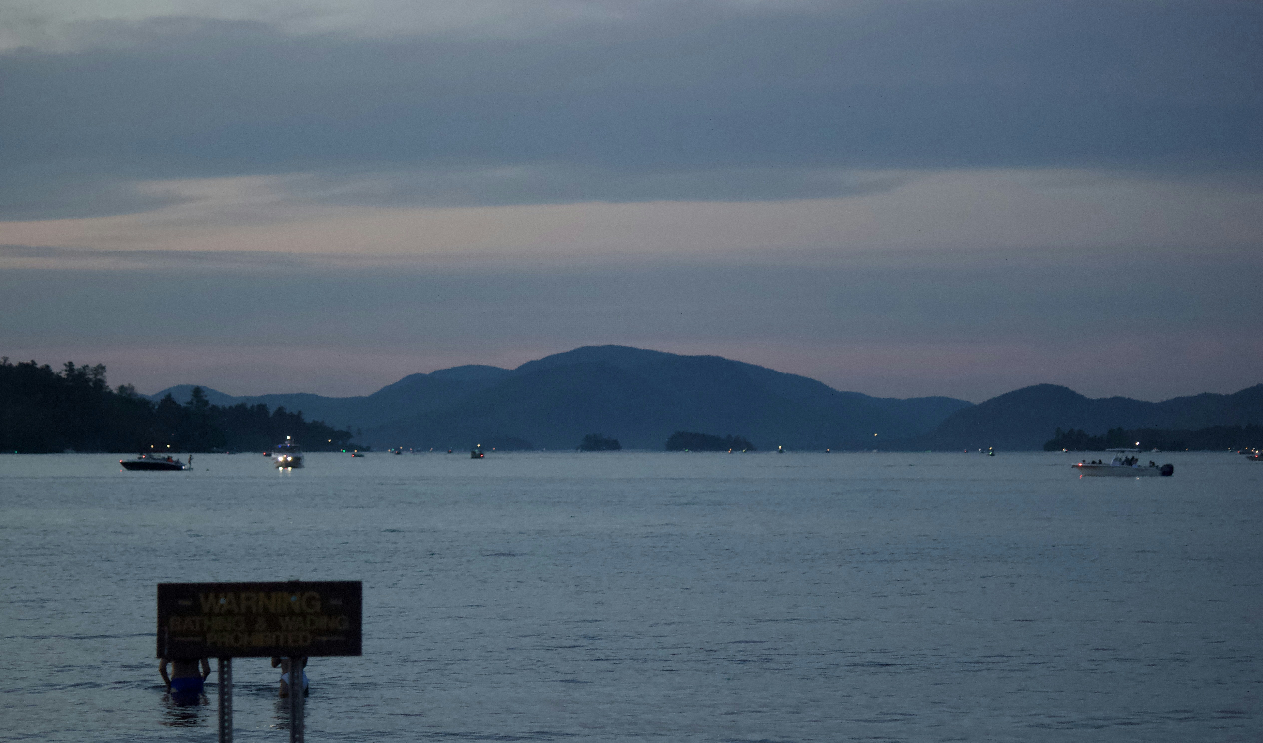 um corpo de água com barcos e montanhas ao fundo