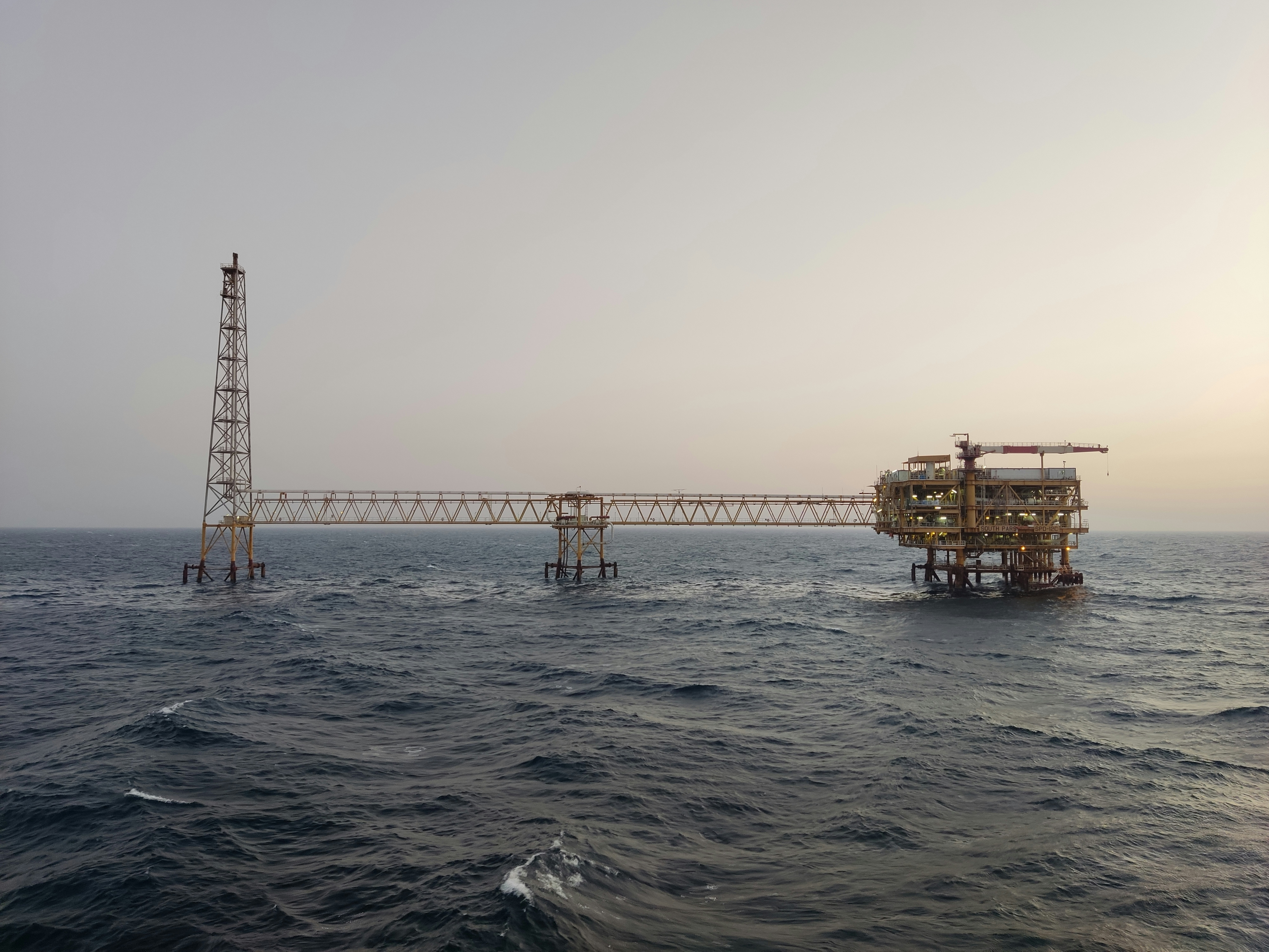 Offshore wellhead platform at sea, dark ocean water, industrial steel structure, atmospheric lighting