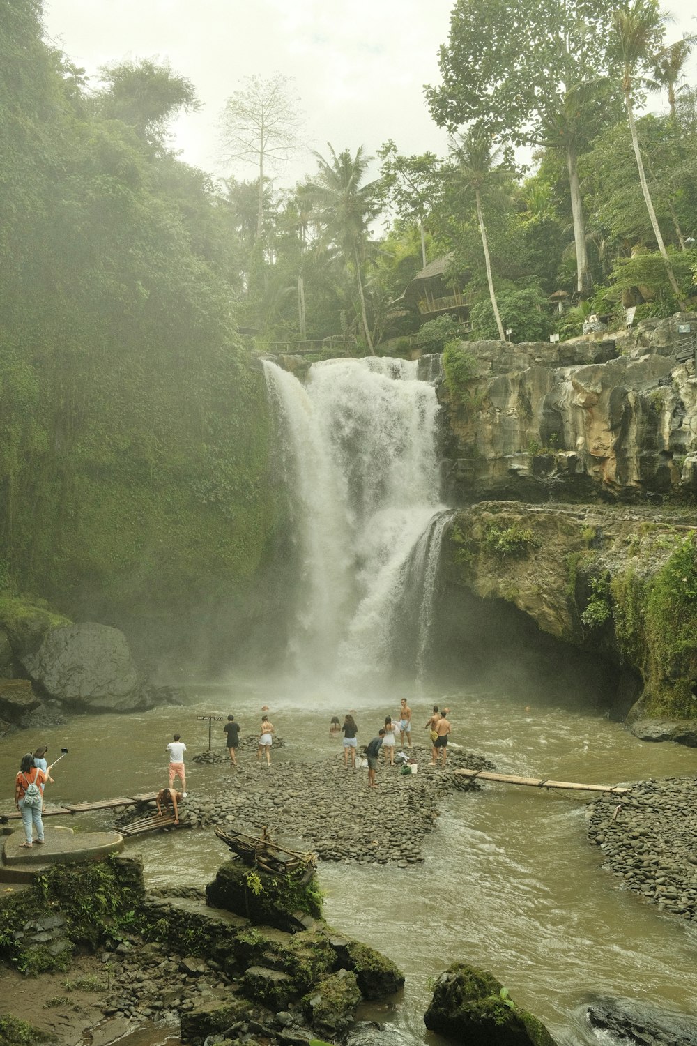 a group of people standing on a rock ledge next to a waterfall