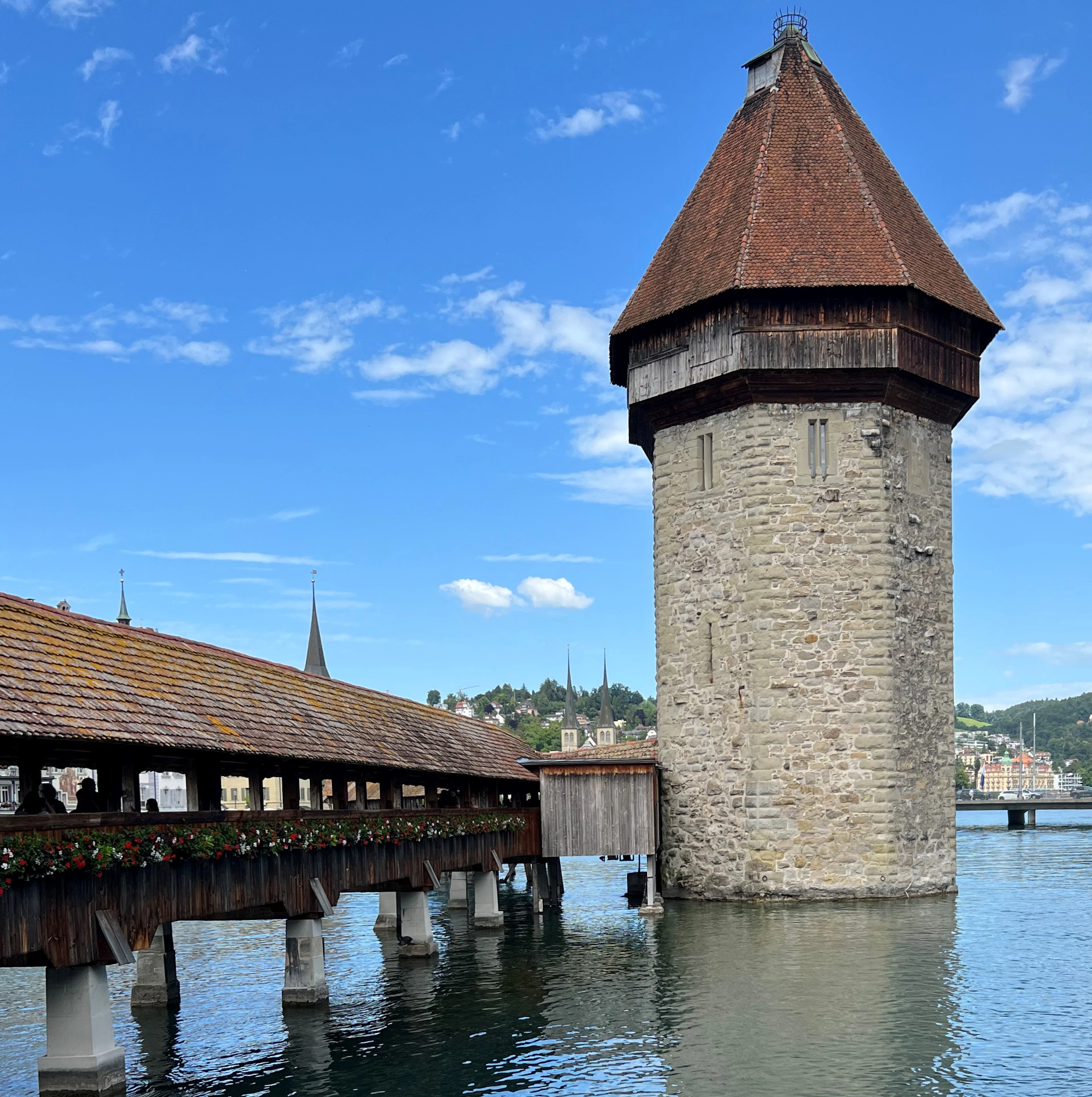 The water tower and the covered timber deck of the Chapel Bridge in Lucerne, flowers along its rail